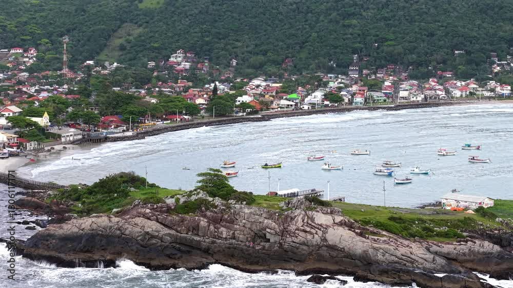 Small fishing boats anchored near a rocky Armacao Beach with a coastal area in the background, Florianopolis, Santa Catarina, Brazil. Small fishing boats anchored near a rocky Armacao Beach with a coastal area in the background, Florianopolis, Santa Catarina, Brazil.