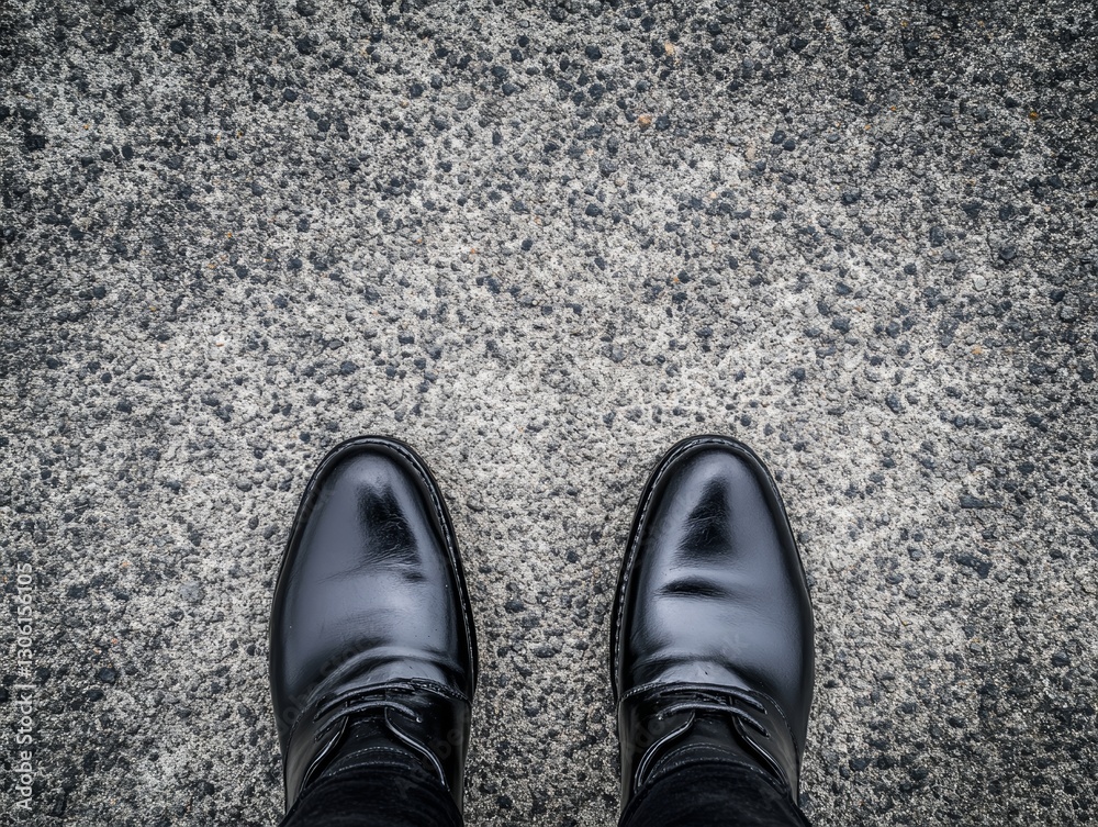 Male feet in black leather shoes on a concrete background Male feet in black leather shoes on a concrete background