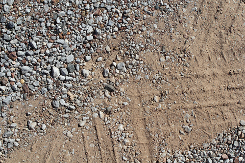 Gravel and dirt with a tire tyre track close-up abstract textured background