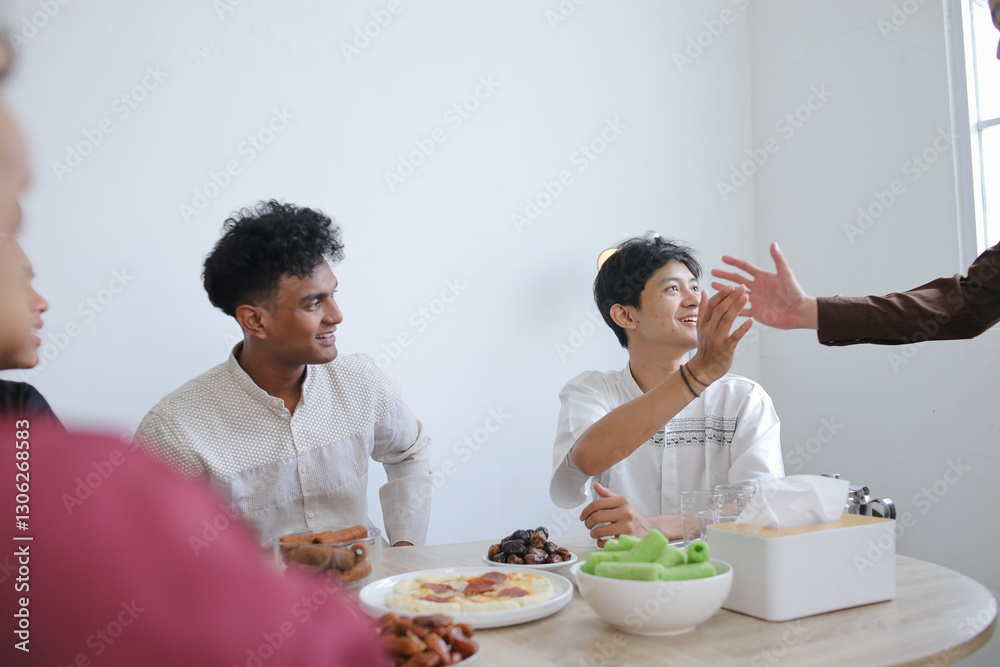 Muslim Friends Shaking Each Other Hands in Dining Table During Ramadan Celebration Muslim Friends Shaking Each Other Hands in Dining Table During Ramadan Celebration