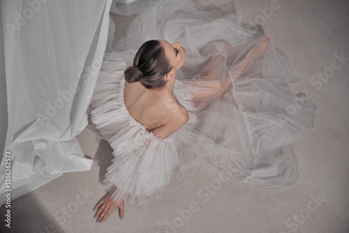 Fotografía dancer sits gracefully on the floor, wearing a delicate tulle dress that flows around her