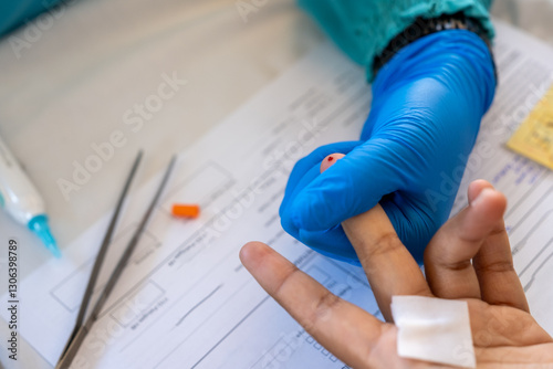 Obraz na płótnie A healthcare worker wearing blue gloves presses a patient's finger after a blood test