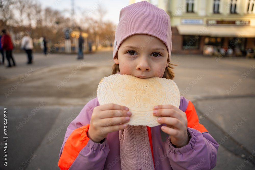 Little girl holding a typical traditional warm waffle or spa waffle in town Karlovy Vary or Carlsbad, Czech Republic Little girl holding a typical traditional warm waffle or spa waffle in town Karlovy Vary or Carlsbad, Czech Republic