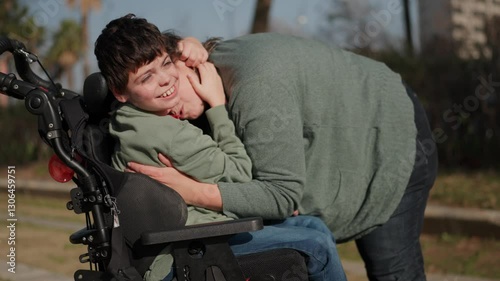 Mother comforting and hugging disabled son in wheelchair photo