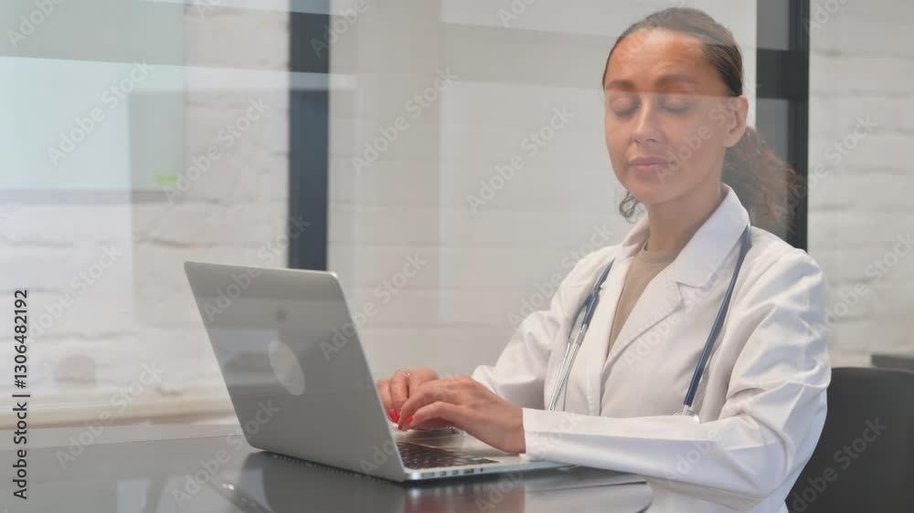 Mixed Race Female Doctor Looking at Camera while Working on Laptop