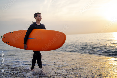 Canvas Print Happy young man is carrying surfboard walking on the beach