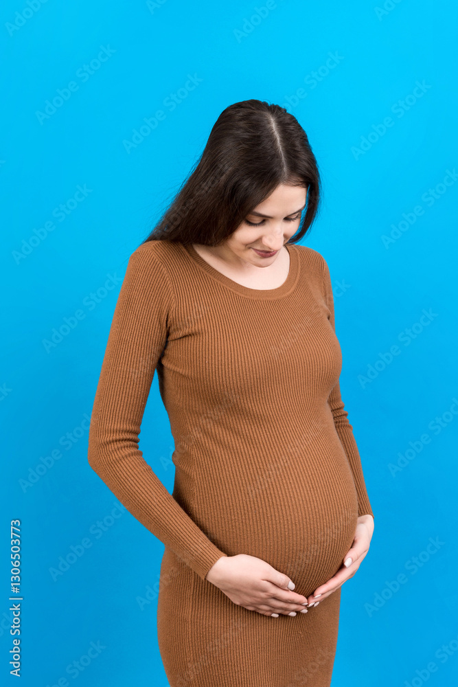 Happy pregnant woman touching her abdomen at Colored background. Future mother is wearing white underwear. Expecting of a baby. Copy space Happy pregnant woman touching her abdomen at Colored background. Future mother is wearing white underwear. Expecting of a baby. Copy space