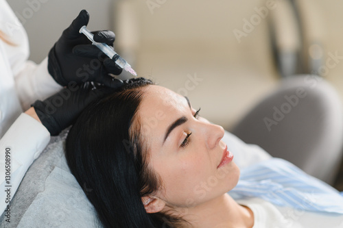 Young woman with hair problem receiving injection in clinic. Hair renewal rejuvenation pampering procedure.