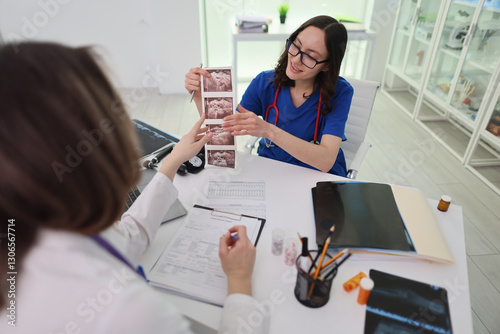 Obraz na płótnie A medical professional carefully reviews diagnostic images with a colleague in a detailed clinical setting w salonie