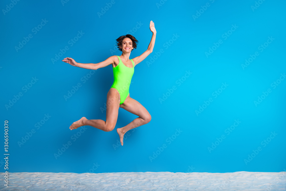 Happy young woman jumping energetically while wearing vibrant swimwear against a vivid blue background showcasing summer vibes and joyful expressions. Happy young woman jumping energetically while wearing vibrant swimwear against a vivid blue background showcasing summer vibes and joyful expressions.