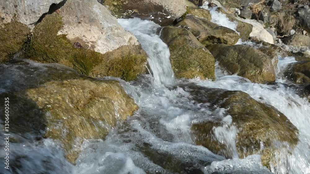 Close-up view of a crystal-clear waterfall cascading over rocks in slow motion. Close-up view of a crystal-clear waterfall cascading over rocks in slow motion.