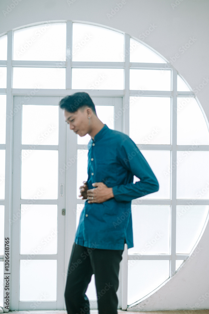 Pensive young man in casual attire standing near geometric window Pensive young man in casual attire standing near geometric window