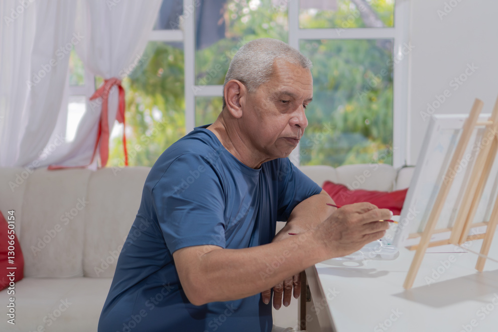 Senior hispanic man painting on canvas at home: concentrated retired painter creating artwork Senior hispanic man painting on canvas at home: concentrated retired painter creating artwork