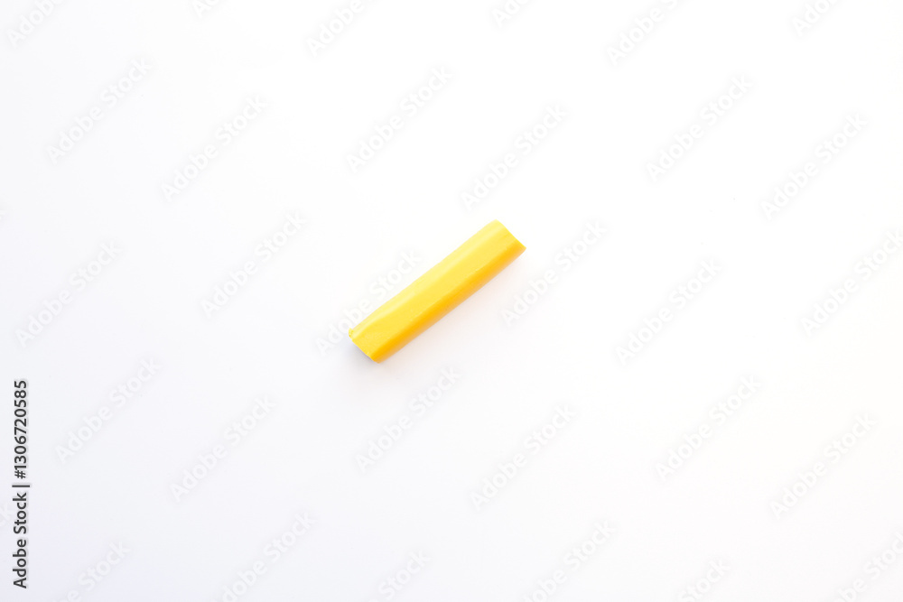 a single piece of yellow modeling clay placed on a white background. The clay is cylindrical in shape and seems to be ready for use in a crafting project. a single piece of yellow modeling clay placed on a white background. The clay is cylindrical in shape and seems to be ready for use in a crafting project.