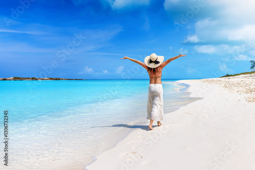 Obraz na płótnie A happy woman with a sunhat walks down a tropical paradise beach in the Caribbean islands, Bahamas w salonie
