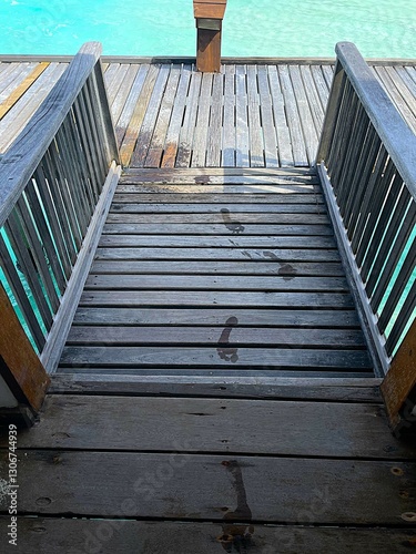 wet footprint of a man on a wooden bridge to an water villa in the maldives