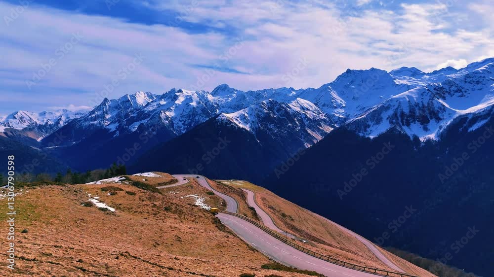 Voitures sur route en lacets, accès à chaînes de montagnes enneigées.  