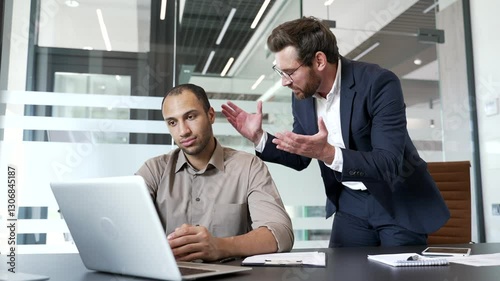 Angry mature boss quarreling with young male subordinate while sitting at workplace in business office. Furious executive arguing talking about problems. Dissatisfied manager unhappy with work results
