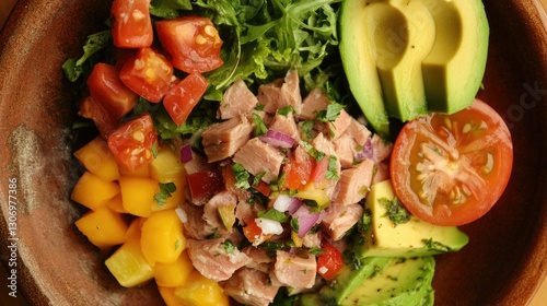 A top-down view of canned tuna with a fresh salad, avocado slices, and colorful vegetables on a rustic plate.