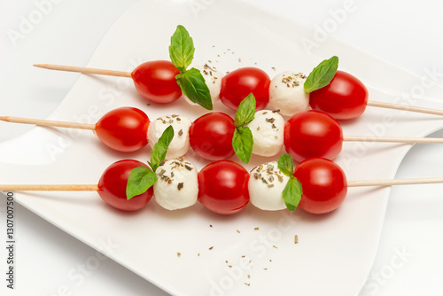 Caprese skewers with tomatoes on a plate on a white background