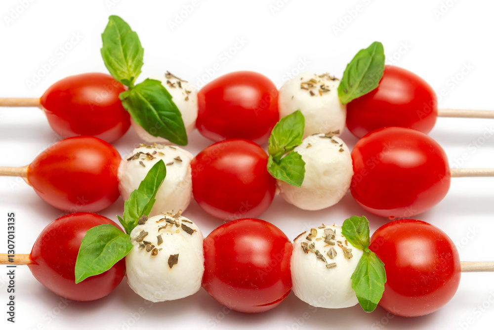 Caprese skewers with cherry tomatoes and basil leaves on a white background Caprese skewers with cherry tomatoes and basil leaves on a white background