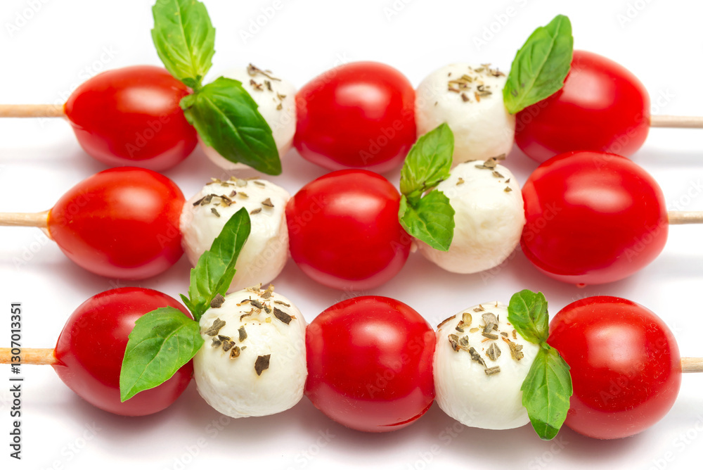 Caprese skewers with tomatoes, mozzarella balls, basil and pesto sauce on white background Caprese skewers with tomatoes, mozzarella balls, basil and pesto sauce on white background