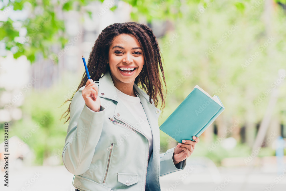 Charming young woman enjoying a sunny walk in the city, holding a notebook and smiling brightly, reflecting joy and leisure outdoors Charming young woman enjoying a sunny walk in the city, holding a notebook and smiling brightly, reflecting joy and leisure outdoors