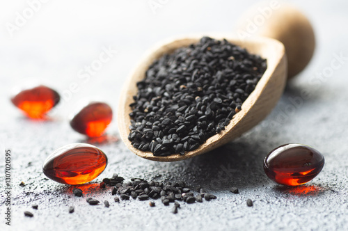 Fototapeta Naklejka Na Ścianę i Meble -  Pills of black cumin seeds essential oil on rustic background. Nigella Sativa capsules, healthy food supplement