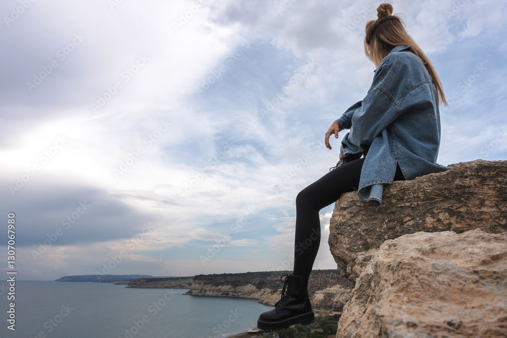 Young Woman Enjoying Peaceful Coastal View from a Cliff Young Woman Enjoying Peaceful Coastal View from a Cliff