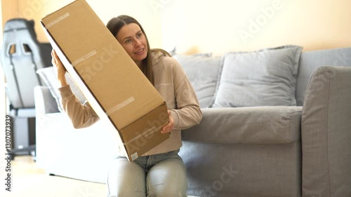 Excited young woman opens a package, removes packing materials, and finally discovers her long-awaited item. Pure joy of unboxing and surprise! Perfect for delivery and e-commerce themes.