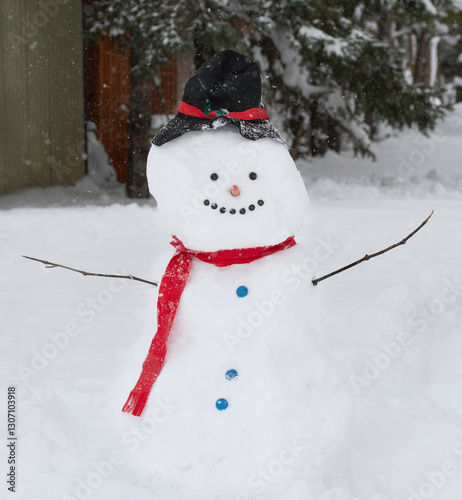 A large snowman with a red scarf, top hat and buttons stands in a snow covered yard.