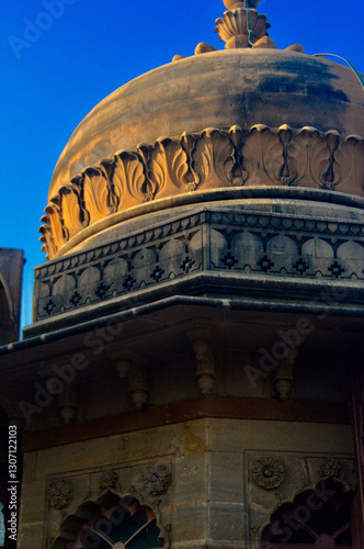 This image captures a close-up view of a historic architectural structure featuring a dome with intricate carvings and decorative details.