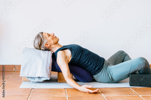 Woman practicing supported restorative yoga with props
