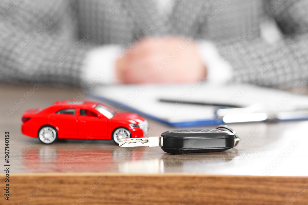 Fototapeta premium Car model and key on wooden table, selective focus. Buying auto