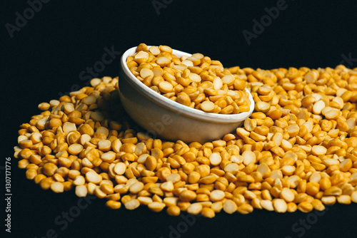 Fototapeta Close-up shot of Organic Bengal Gram (Cicer arietinum) placed in a ceramic white bowl, with split yellow chana dal forming the gradient background
