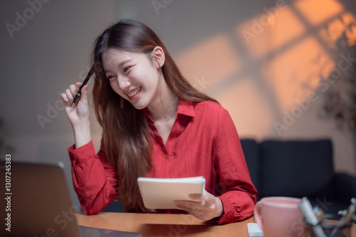 Konstfotografi Happy young entrepreneur working from home at night, jotting down ideas in a not