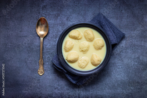 Rasmalai is a soft, spongy Indian dessert made of chhena (paneer) dumplings soaked in sweet, flavored milk, garnished with saffron, cardamom, and nuts. photo