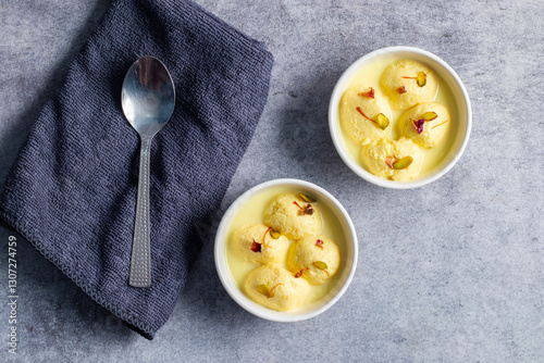 Rasmalai is a soft, spongy Indian dessert made of chhena (paneer) dumplings soaked in sweet, flavored milk, garnished with saffron, cardamom, and nuts. photo