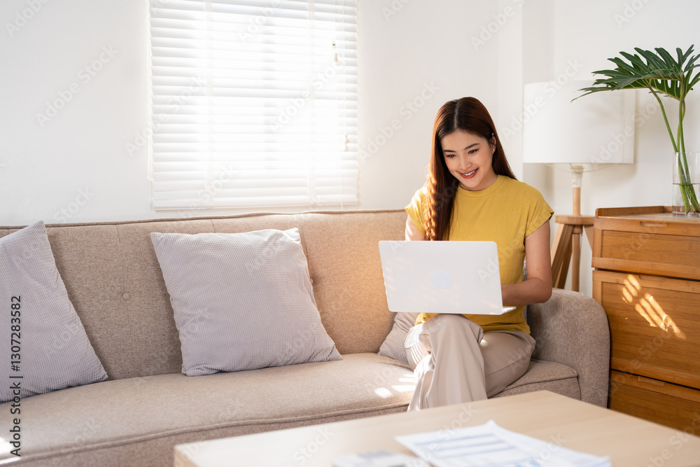 Relaxed happy young woman sitting on sofa using laptop at home surfing, doing online ecommerce shopping, looking at computer ordering sale products on website, watching videos or e learning. Relaxed happy young woman sitting on sofa using laptop at home surfing, doing online ecommerce shopping, looking at computer ordering sale products on website, watching videos or e learning.