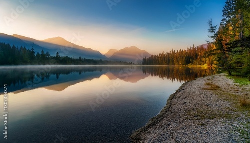 tranquil lakeside view at dawn with reflective water and misty mountains in the background