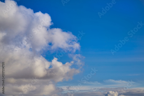 Canvas Print Fluffy, snow-white clouds with subtle sunlit shadows slowly drift across the serene blue sky
