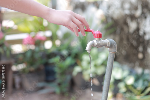 A woman's hand is opening or closing the water from the tap for cleaning.