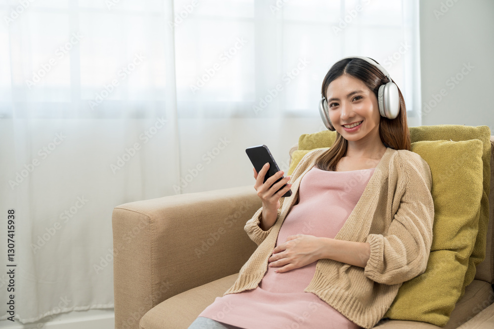 Happy pregnant young woman holding headphone on her womb at home, relaxed young asian mother let her fetal listening to music, family planning and pregnancy with insurance for child health. Happy pregnant young woman holding headphone on her womb at home, relaxed young asian mother let her fetal listening to music, family planning and pregnancy with insurance for child health.