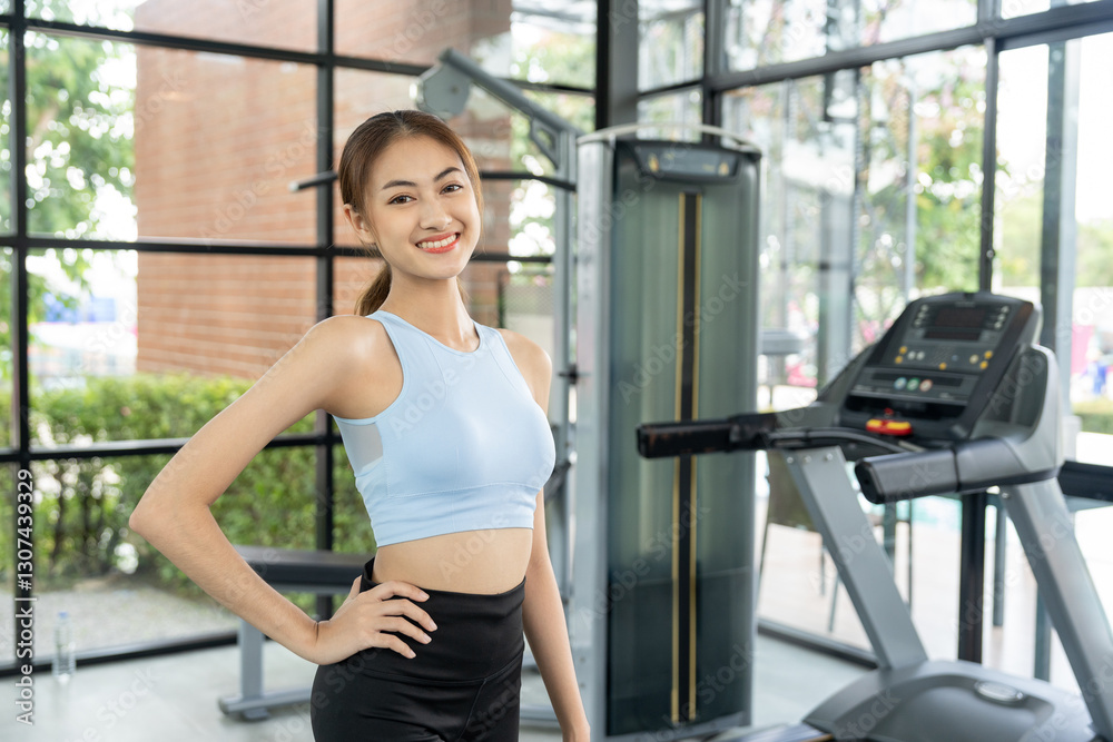 Fototapeta premium Young beautiful asian woman wearing sportswear warming up in fitness gym before exercise. Attractive Woman stretching before running workout. Training athlete at Fitness Center