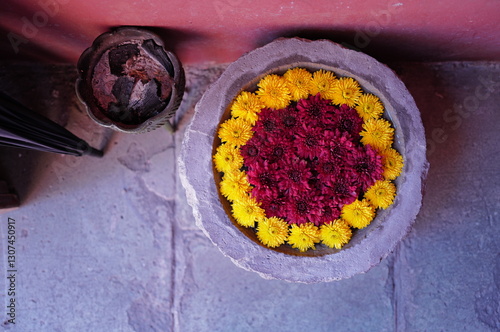 Marigold and chrysanthemum flowers arranged in a circular pattern on stone. photo