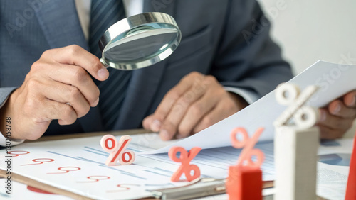 Businessman analyzing financial growth with magnifying glass and percentage symbols. Investment and profitability.
