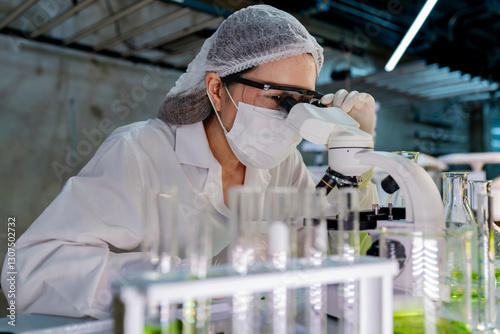 A researcher in a sterile lab conducts a scientific experiment using a microscope and test tubes. Cutting edge biotechnology and chemistry help develop breakthroughs in medicine and healthcare. photo