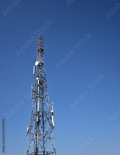 A metal telecommunications tower stands tall against a clear blue sky.