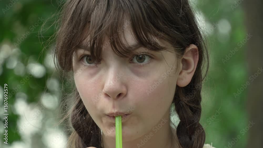 A sad teenage girl with pigtails drinks a refreshing beverage through a straw on a summer day in a city park. Front shot, close-up A sad teenage girl with pigtails drinks a refreshing beverage through a straw on a summer day in a city park. Front shot, close-up