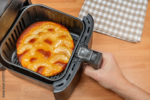 Hand holding freshly baked homemade apple pie in air fryer at the kitchen. Top view.